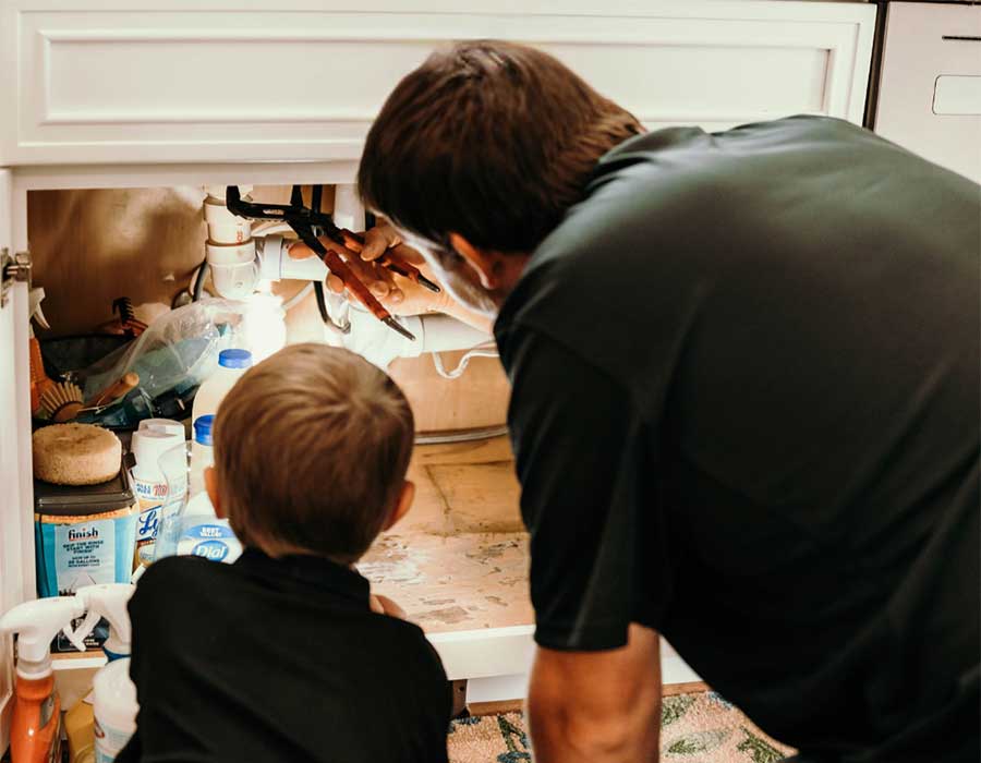 Emergency plumbing technician repairing an under-sink pipe connection